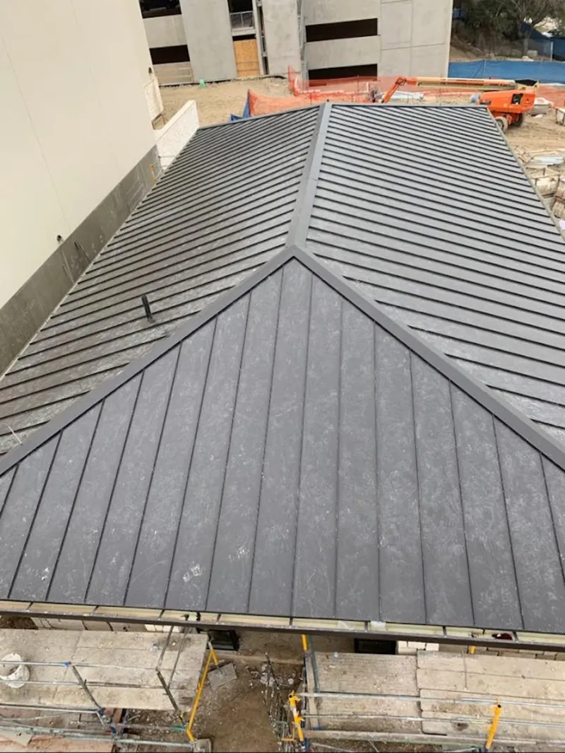 Commercial metal roof construction with crane equipment in Mango